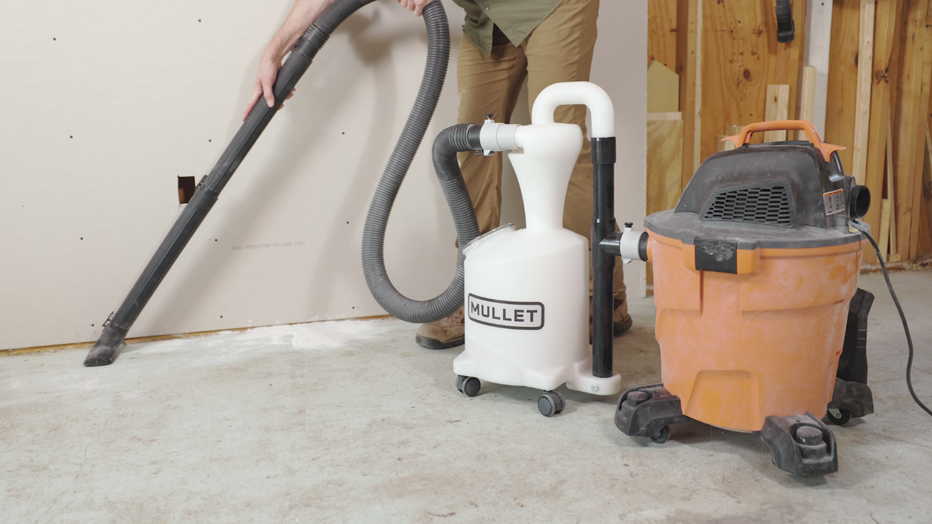 The M5 Dust Cyclone Collection connected to a shop vac vacuuming up drywall dust from the floor